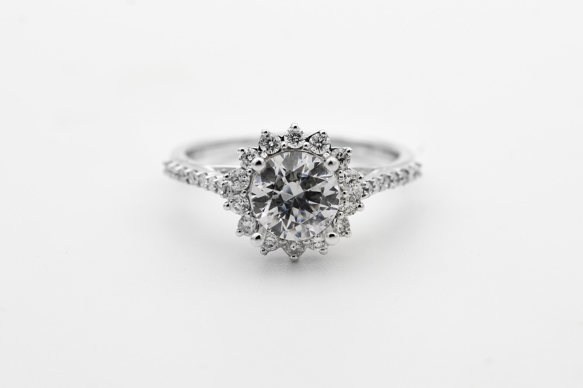 a silver engagement ring featuring a round cut center diamond and a floral inspired halo