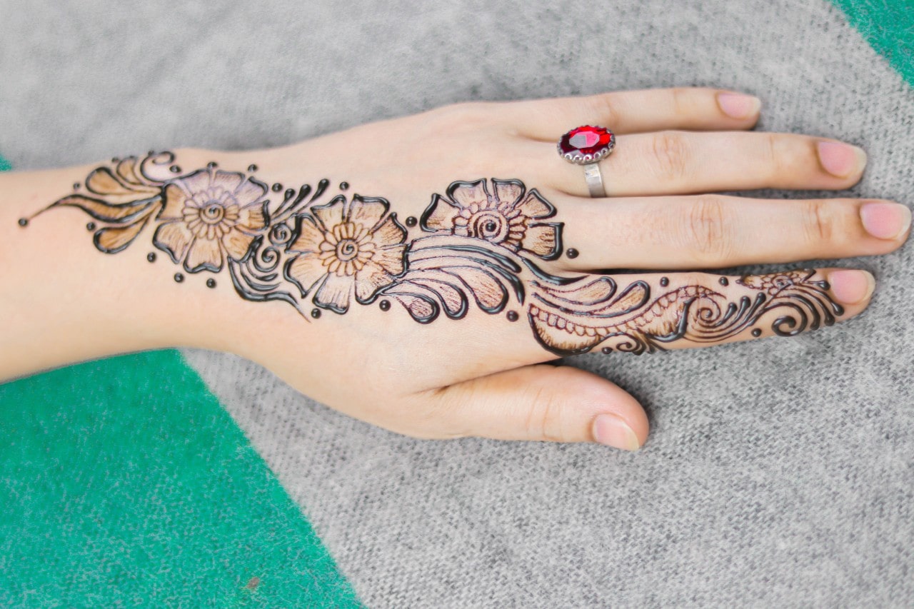 Red garnet ring worn by a hand with a henna-tattoo