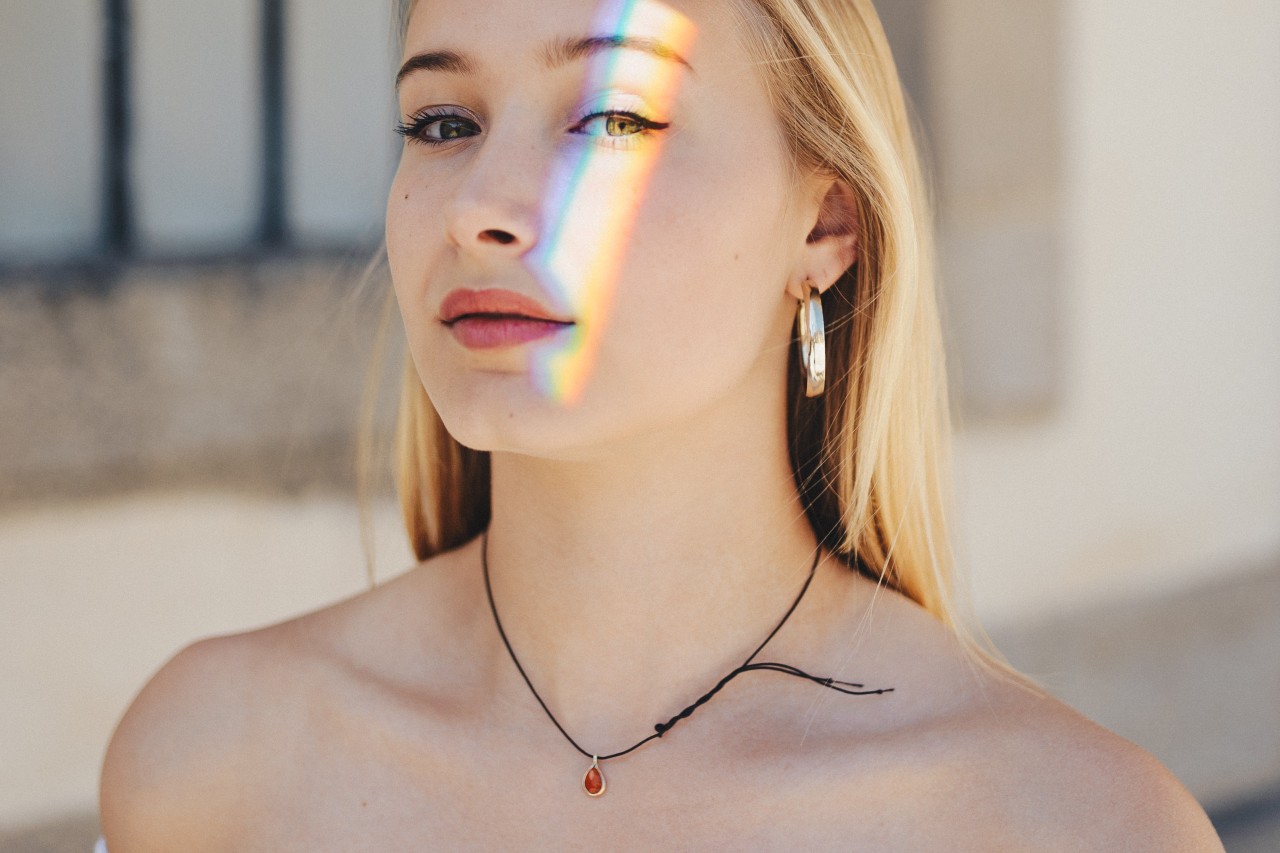 Lady wearing a red garnet and yellow gold pendant on a cord necklace