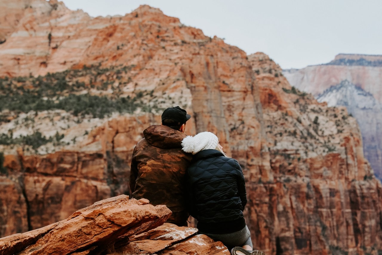 A couple sits and admires the landscape on a hike