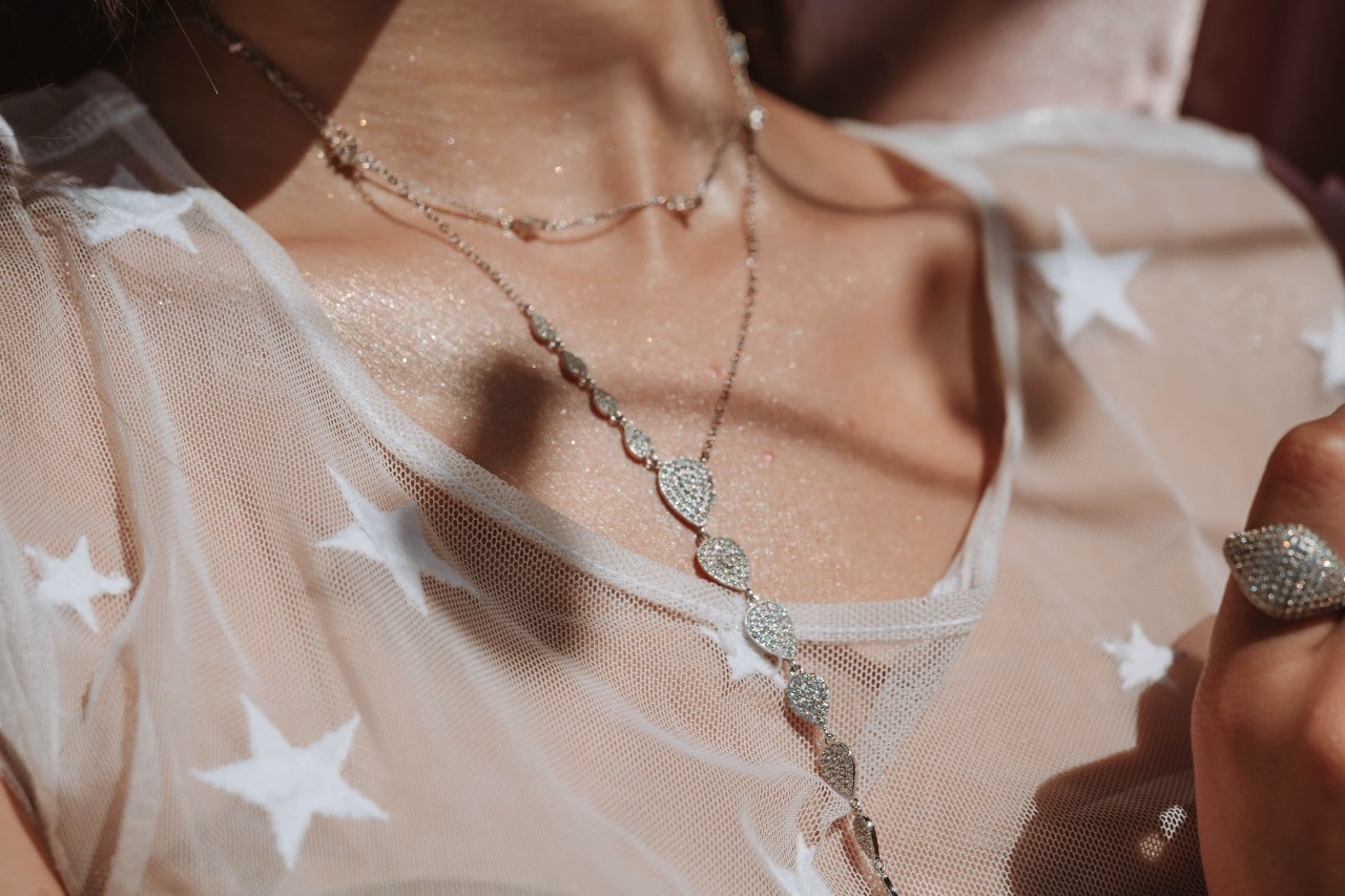 close up image of a woman’s neckline wearing diamond necklaces and a star printed shirt