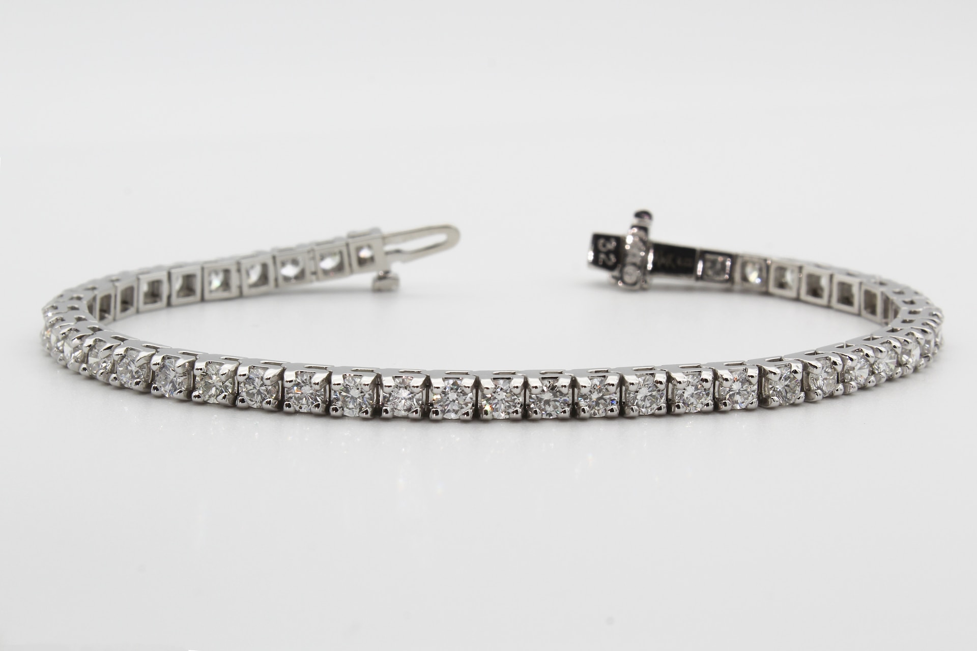 a white gold diamond tennis bracelet against a gray background