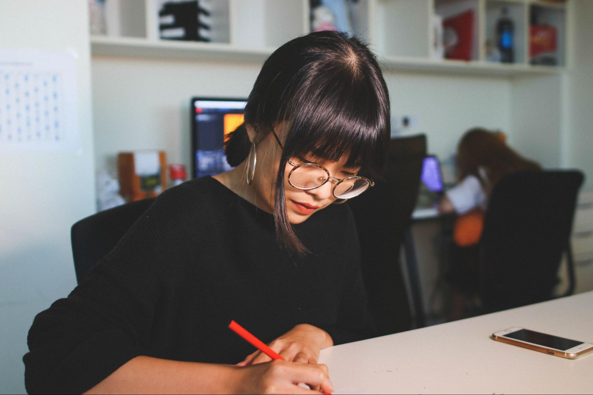 a woman wearing hoop earrings studies at a desk.