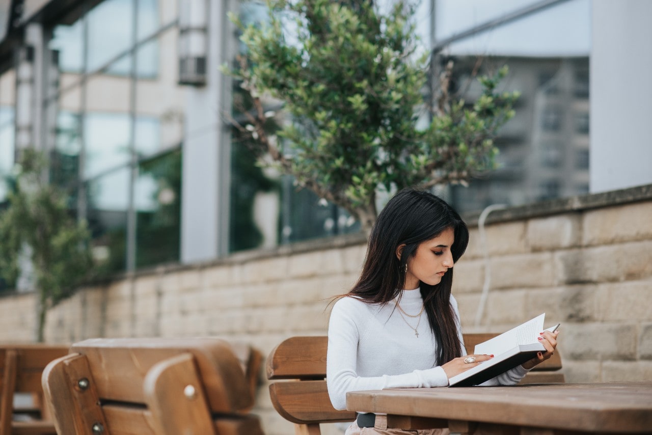 a woman reads a textbook outside her classes.