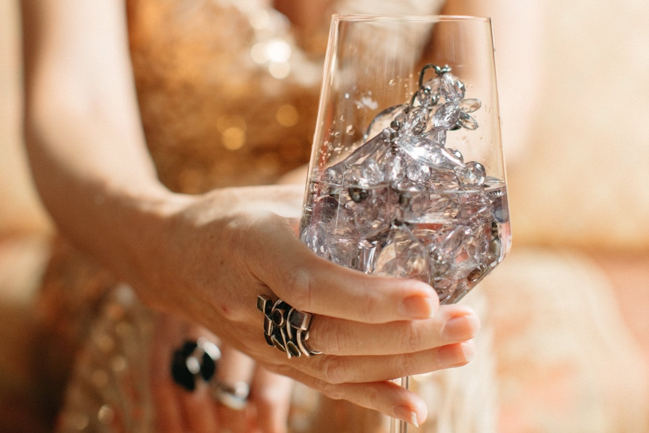 A woman swirls a wine glass filled with water at a formal party.