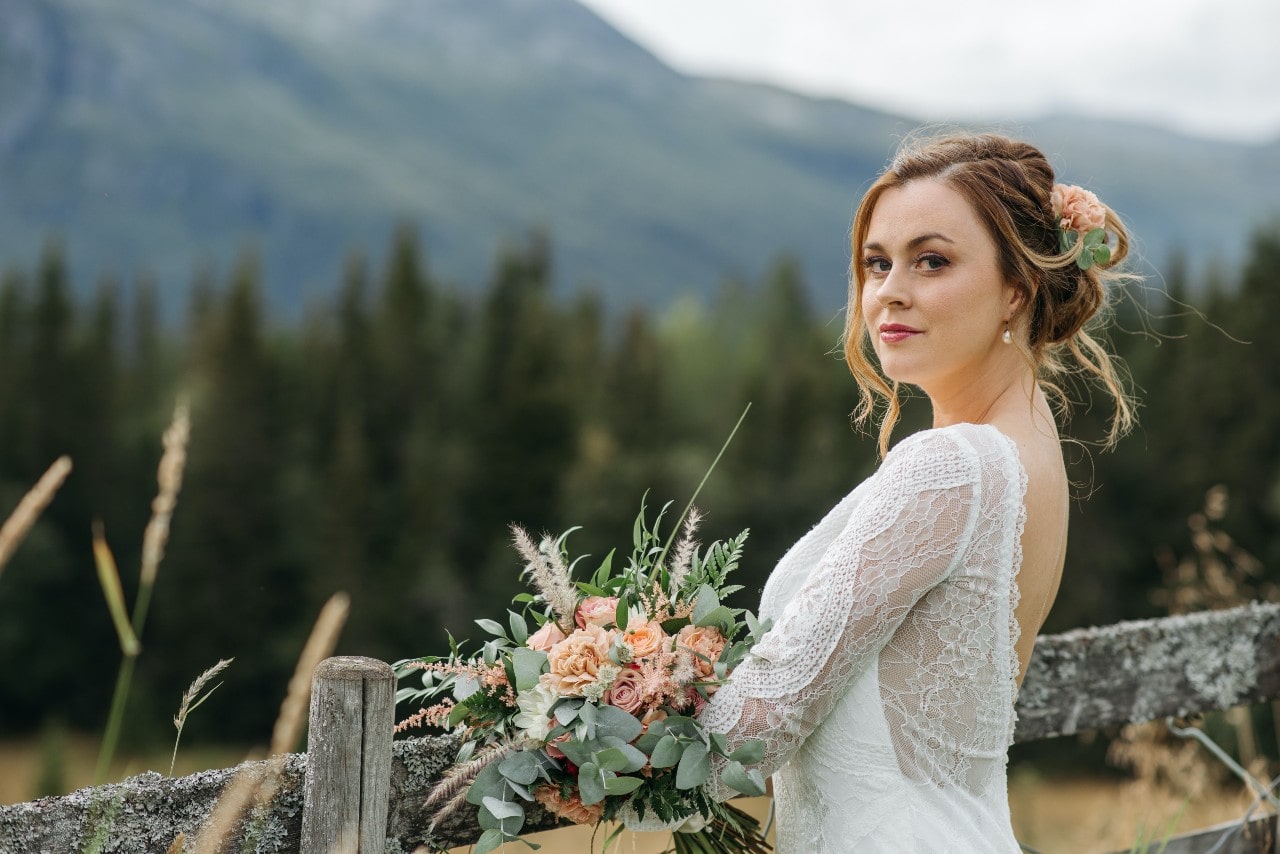 An elegant bride-to-be looking at the camera as she is photographed in a breathtaking mountain setting.