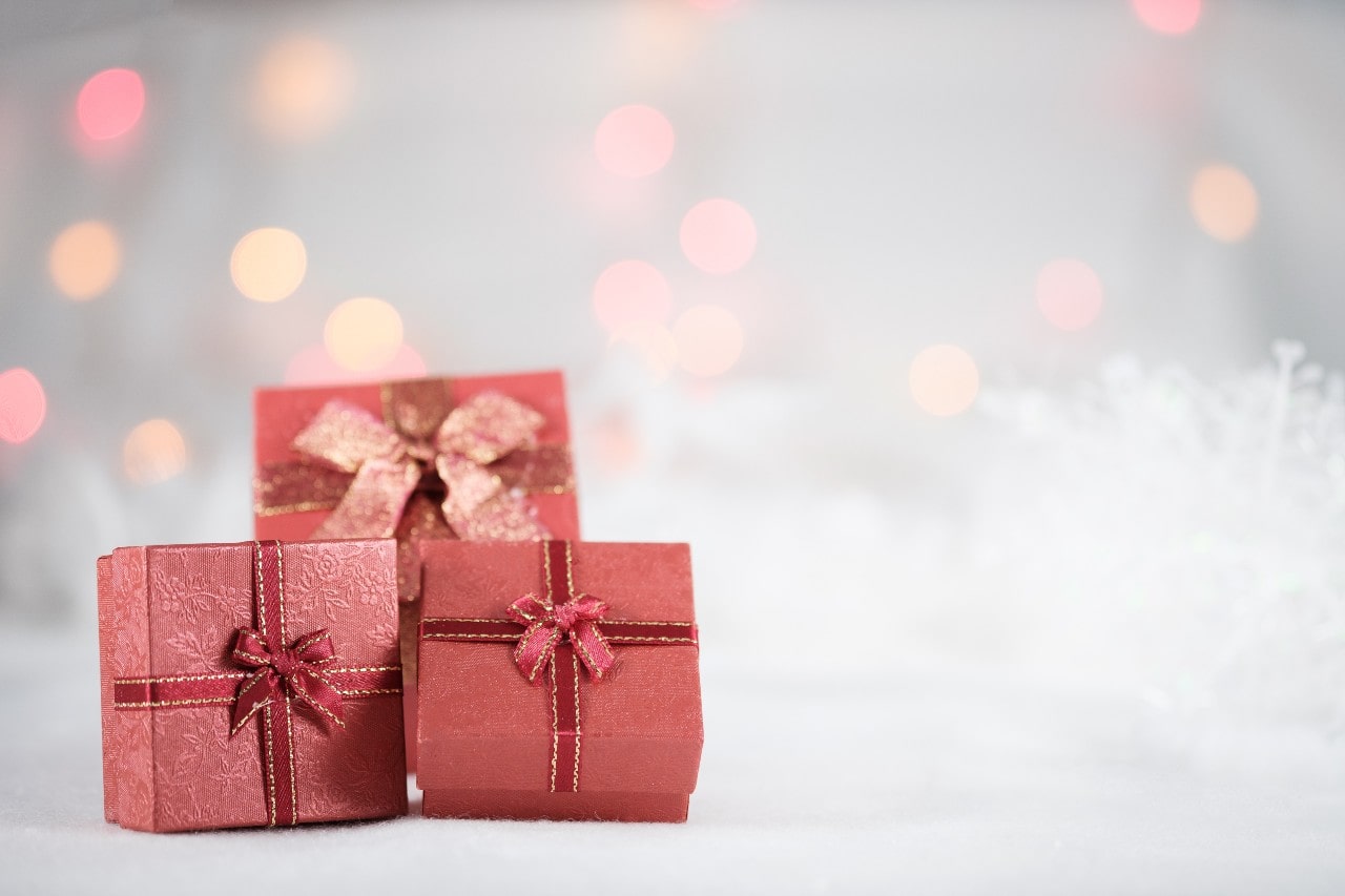 A close-up of three small, similarly wrapped gifts on a festive backdrop.