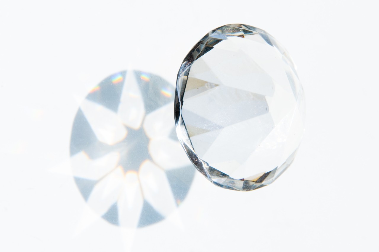 close up image of a diamond and its shadow on a white background