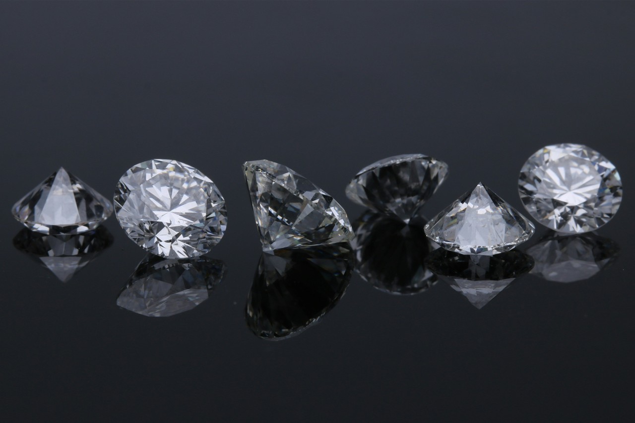 a row of round cut diamonds sitting on a dark reflective surface