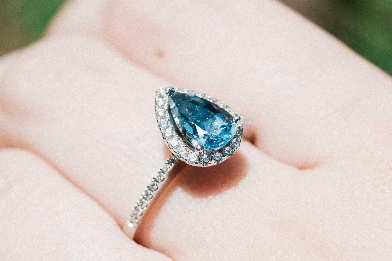 a close up image of a white gold fashion ring featuring a blue gemstone