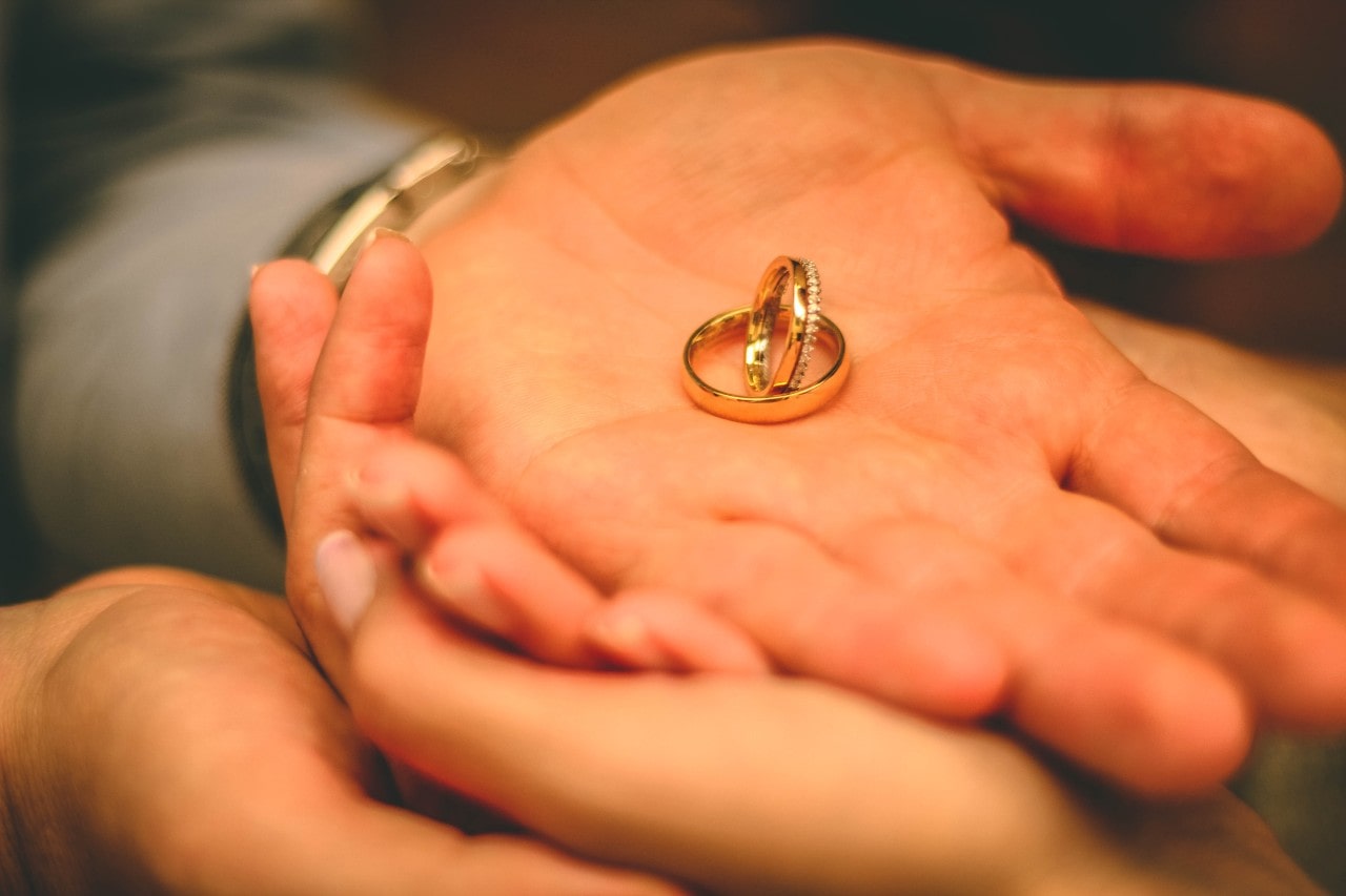 Two gold wedding rings sit in a man’s palm.