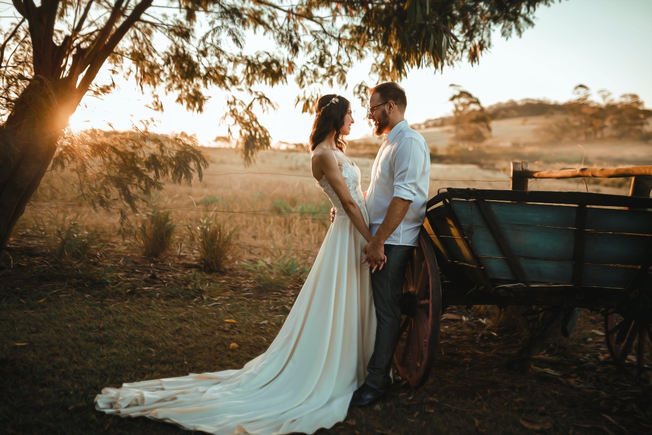 A couple share an intimate moment by a waggon as the sun sets.