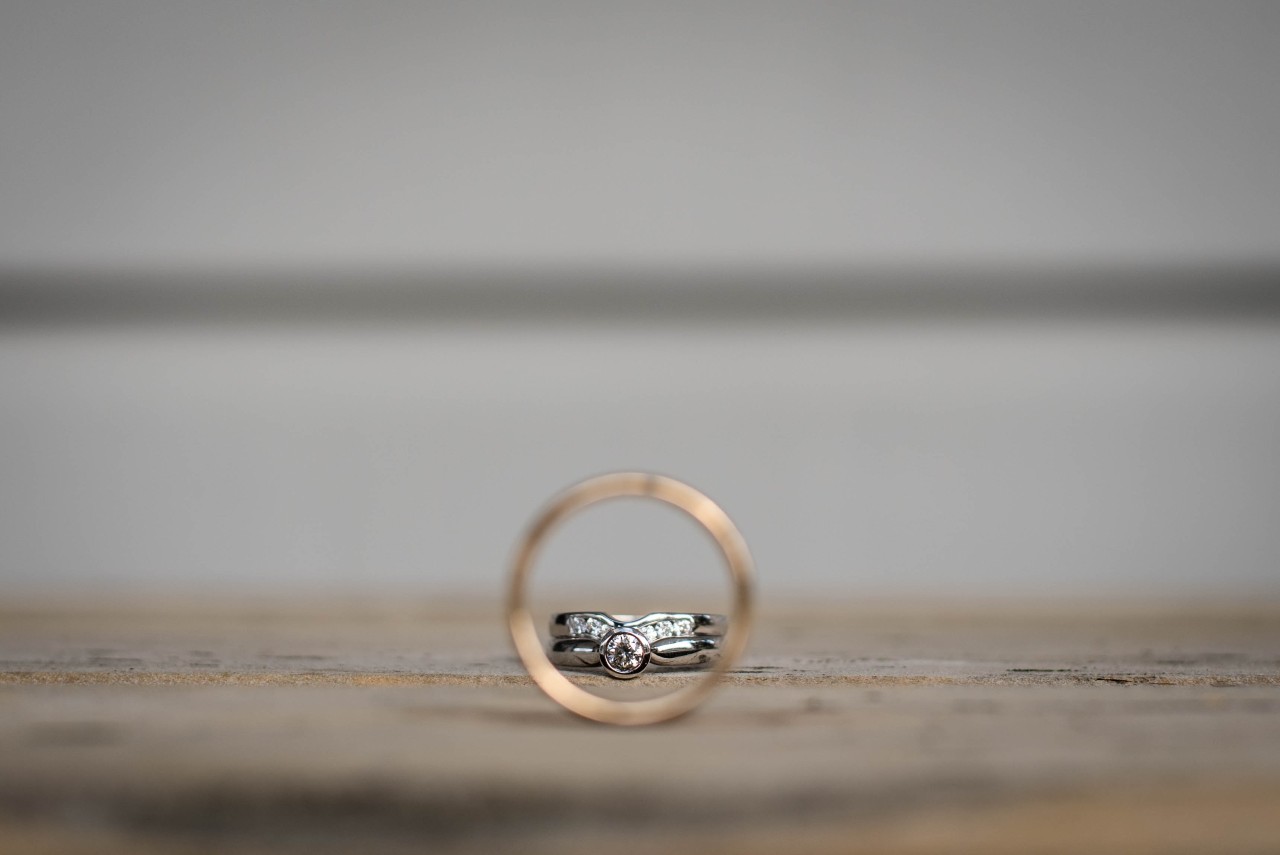 A view of a women’s wedding ring set through a gold men’s band.