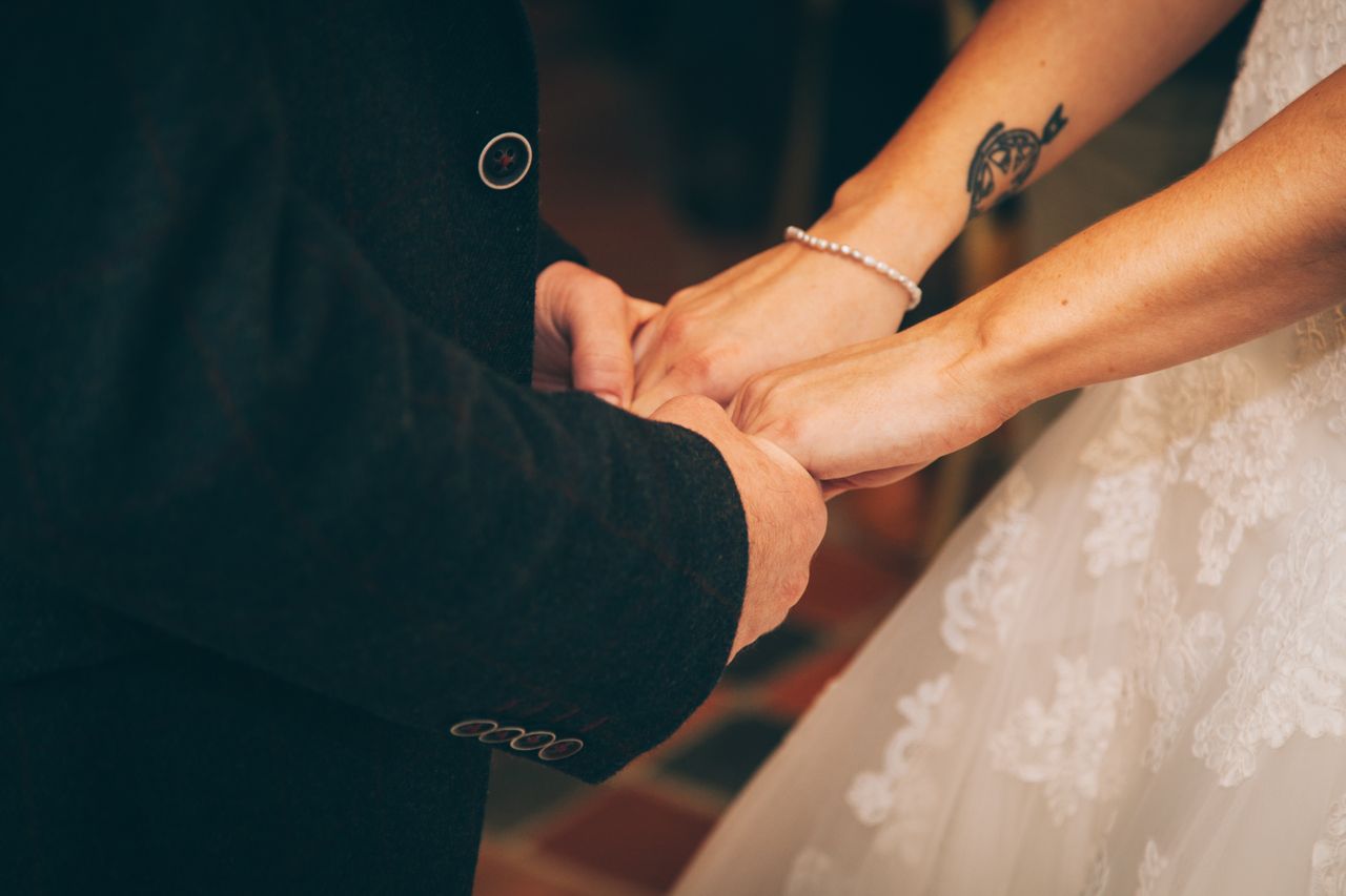 a bride and groom holding hands, the bride wearing a delicate bracelet