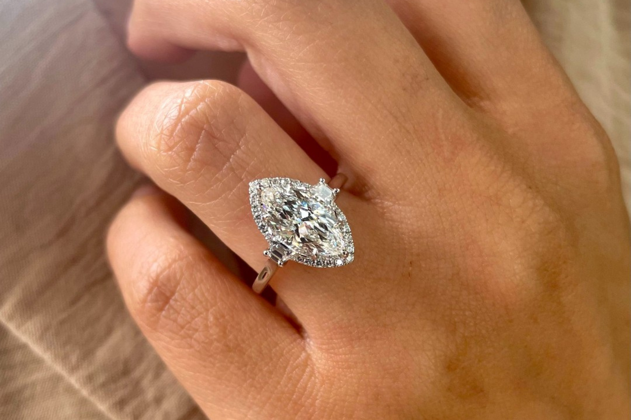 a woman’s hand placed on her cheek and donning an engagement ring a woman’s hand placed on her cheek and donning an engagement ring