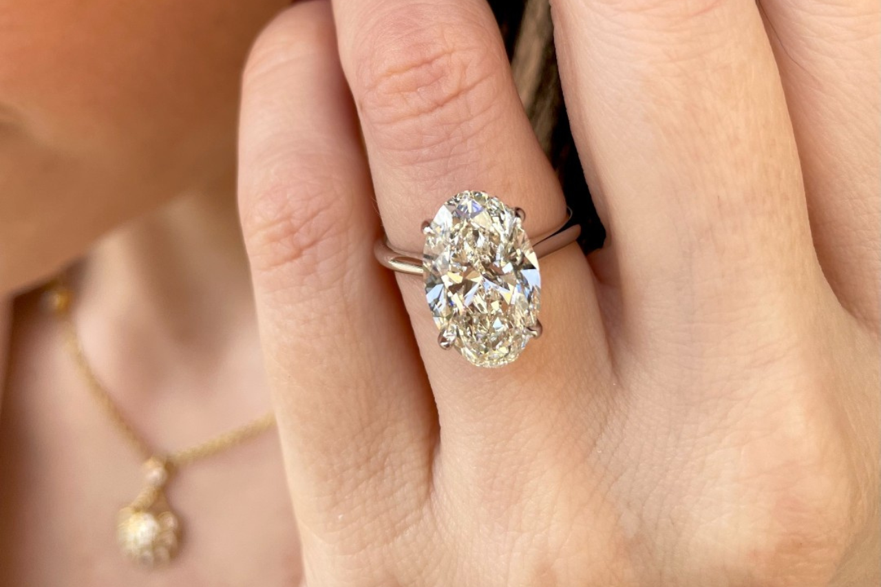 a woman’s hand, donning a white gold marquise cut engagement ring, being held by a man’s hand a woman’s hand, donning a white gold marquise cut engagement ring, being held by a man’s hand