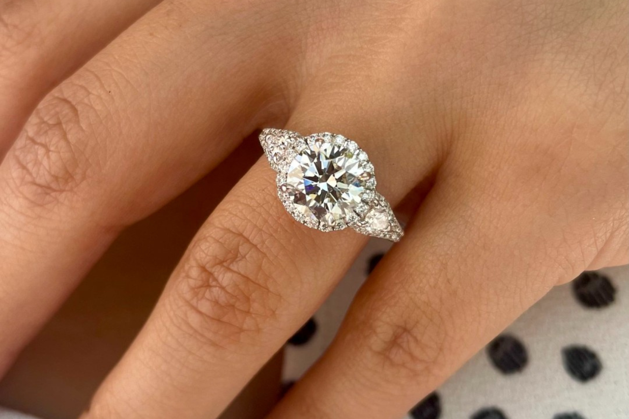 a couple intertwining their pinkies, the woman wearing a white gold halo engagement ring a couple intertwining their pinkies, the woman wearing a white gold halo engagement ring