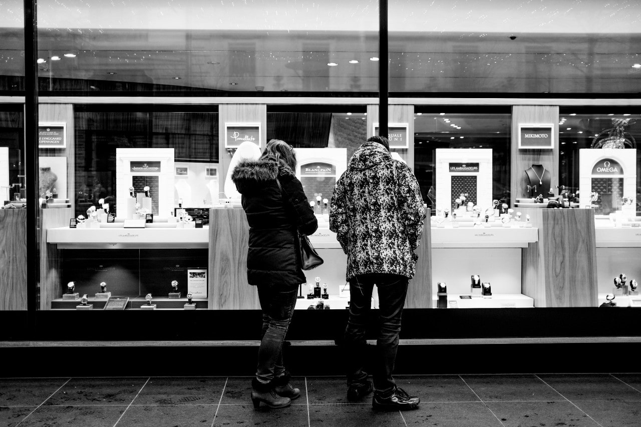 A black and white photo of a young couple window shopping at a luxury jewelry store.