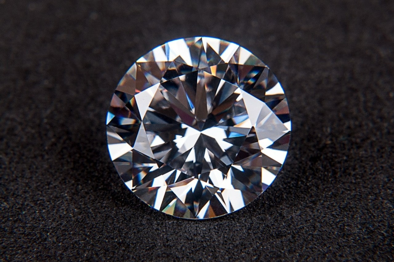 A close-up of a stunning round cut diamond on a soft fabric background.