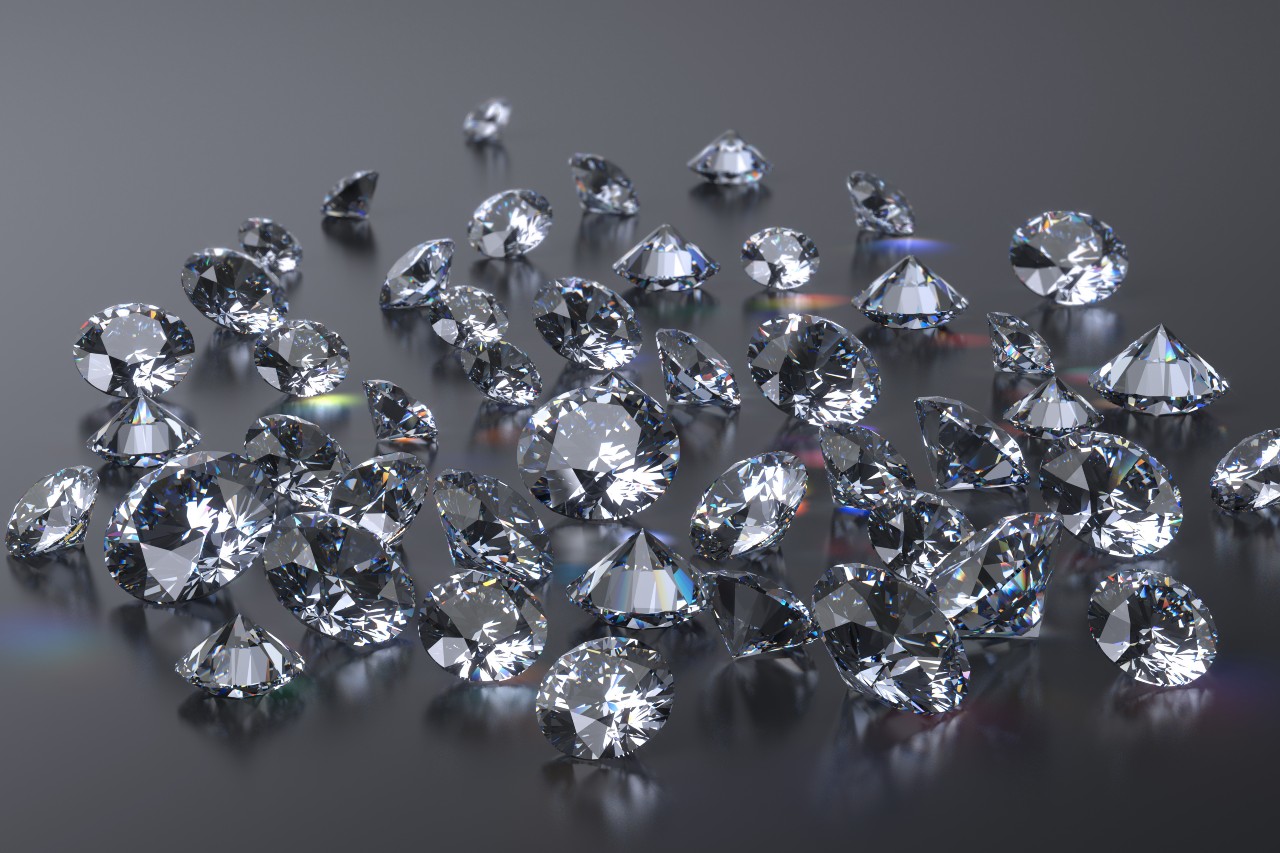 A handful of dazzling round cut diamonds displayed on a dark, reflective surface.