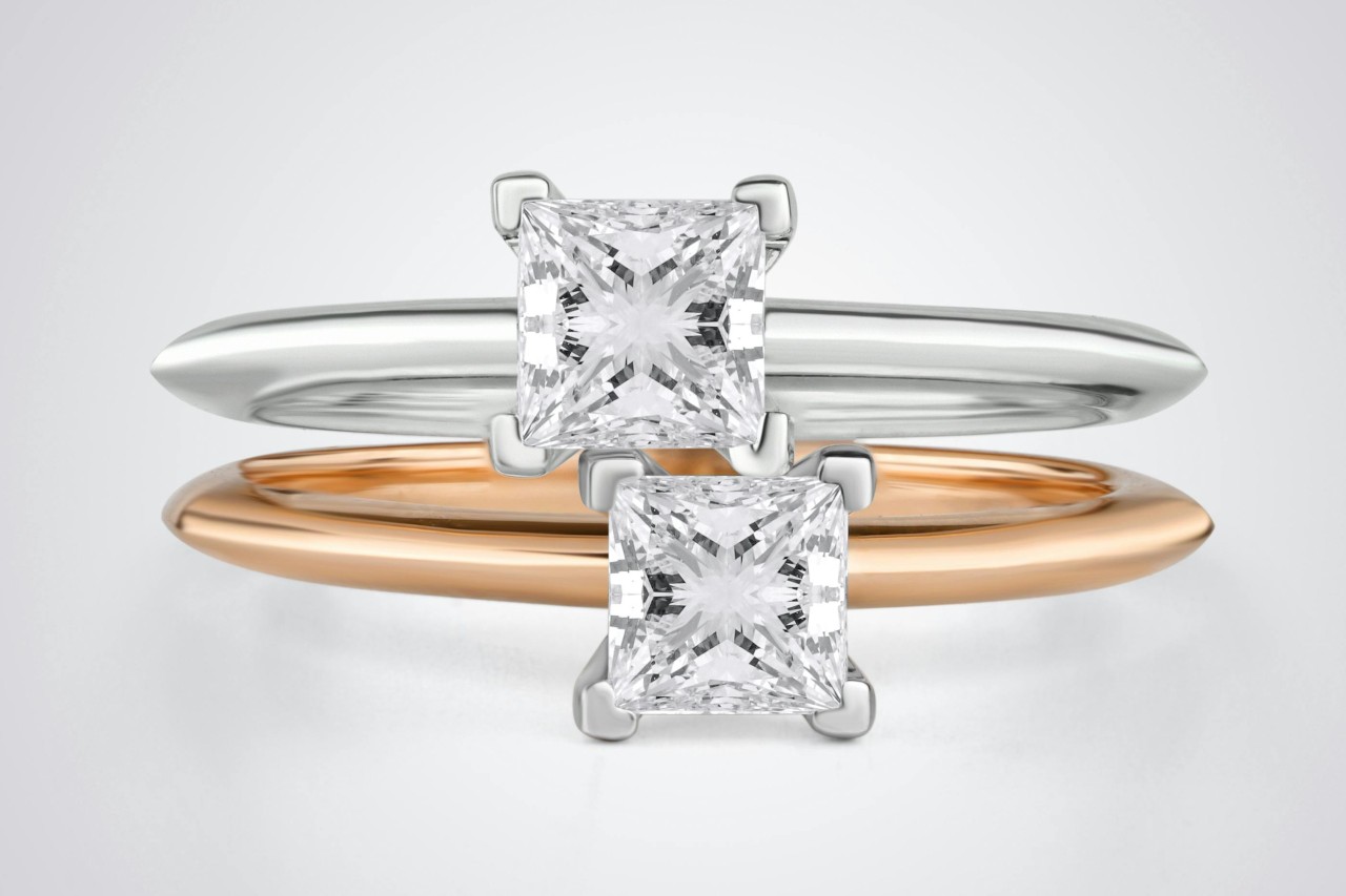 Two princess cut diamond solitaire rings, one white gold and the other rose gold.