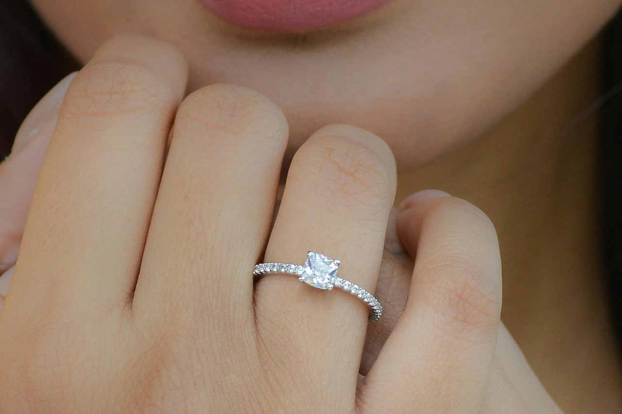 A woman wearing a platinum side stone ring with a radiant center stone diamond.