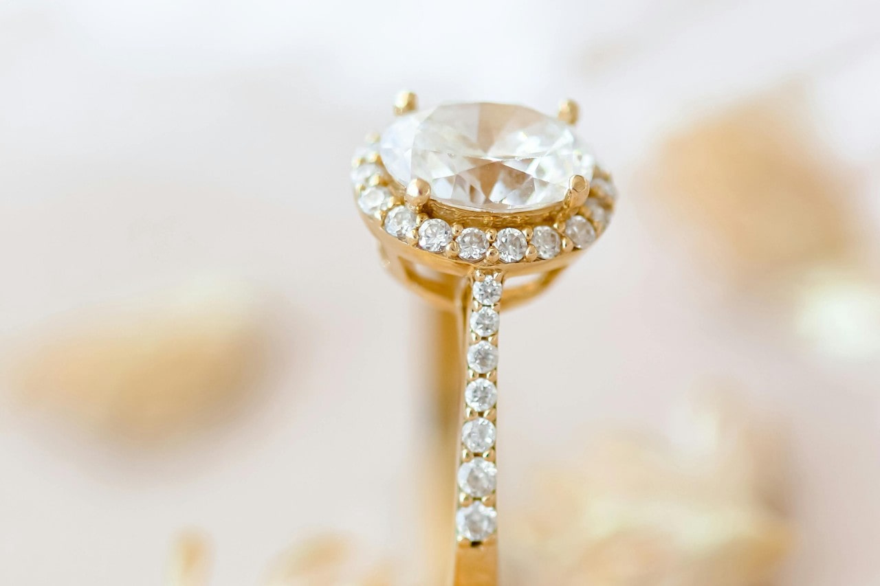 A yellow gold diamond halo engagement ring with side stone details