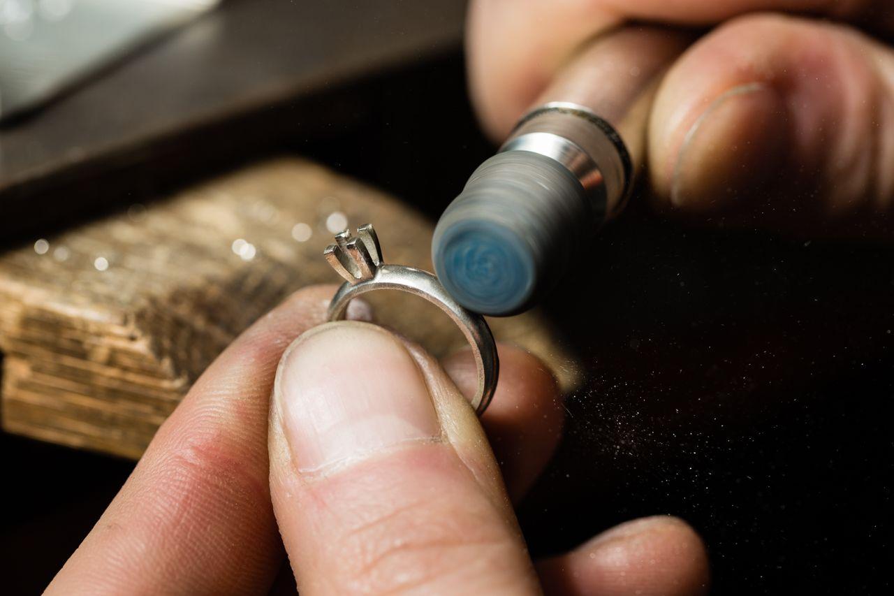 close up image of a jeweler buffing the sides of a white gold ring