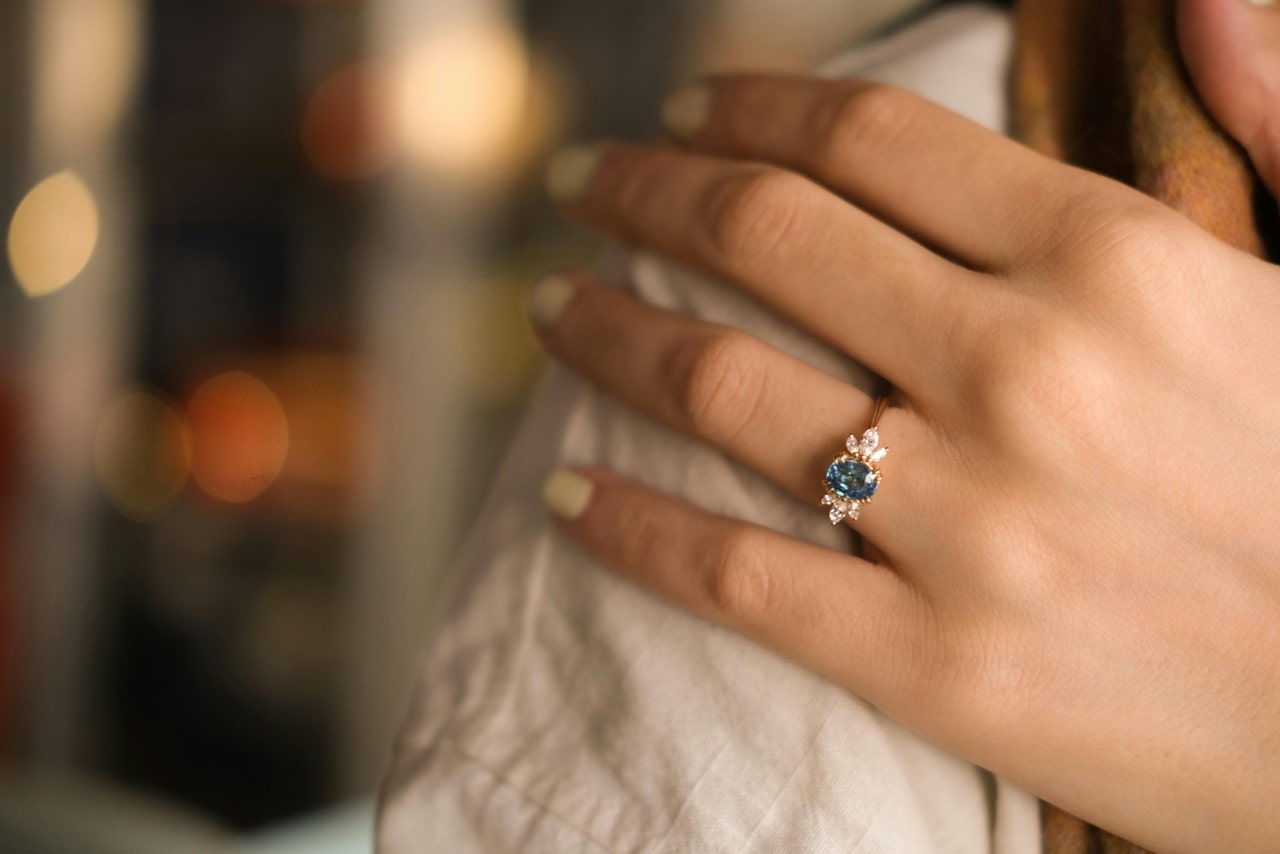 A yellow gold and blue topaz engagement ring with diamond accent stones around the blue center stone.